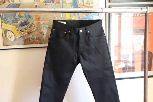 Black pants hanging on a rack with a colorful poster in the background
