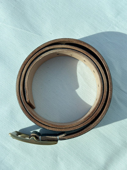 Brown leather belt with a metal buckle on a light blue background